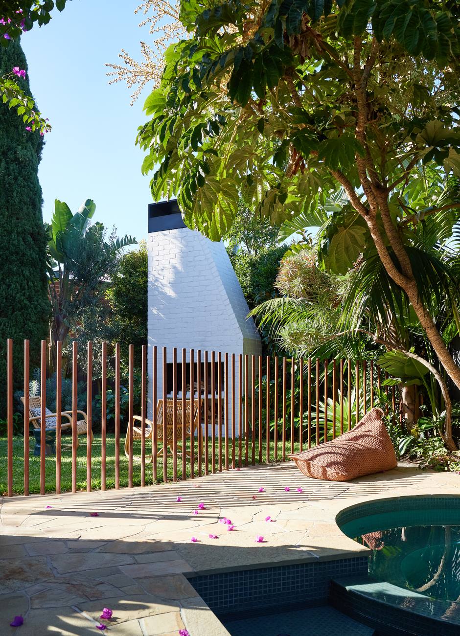 The copper rod fence with the fireplace and lawn beyond, seen from the pool paving