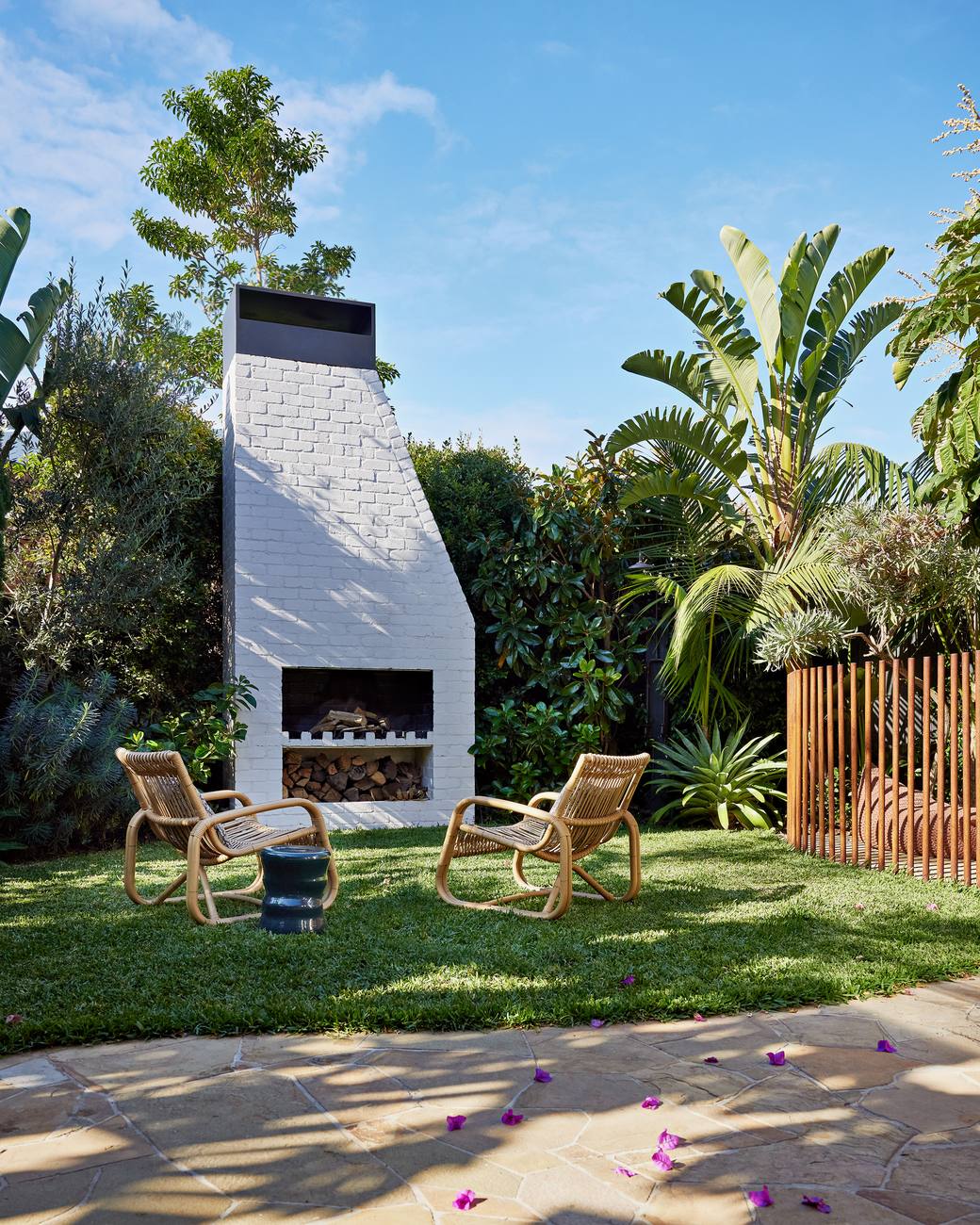 The white brick fireplace on the lawn with a pair of cane chairs drawn up to it