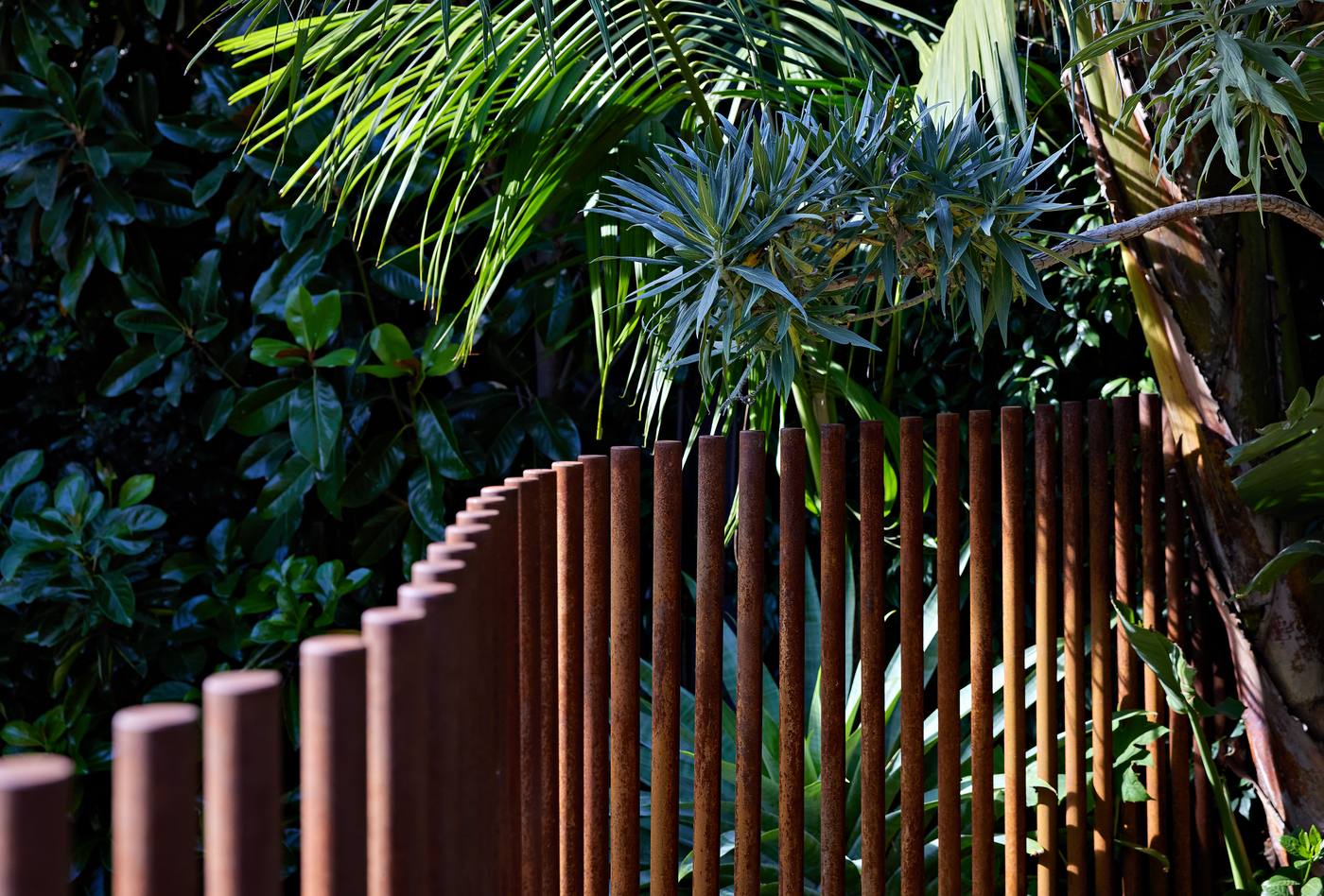The copper rod fence curving away into deep planting