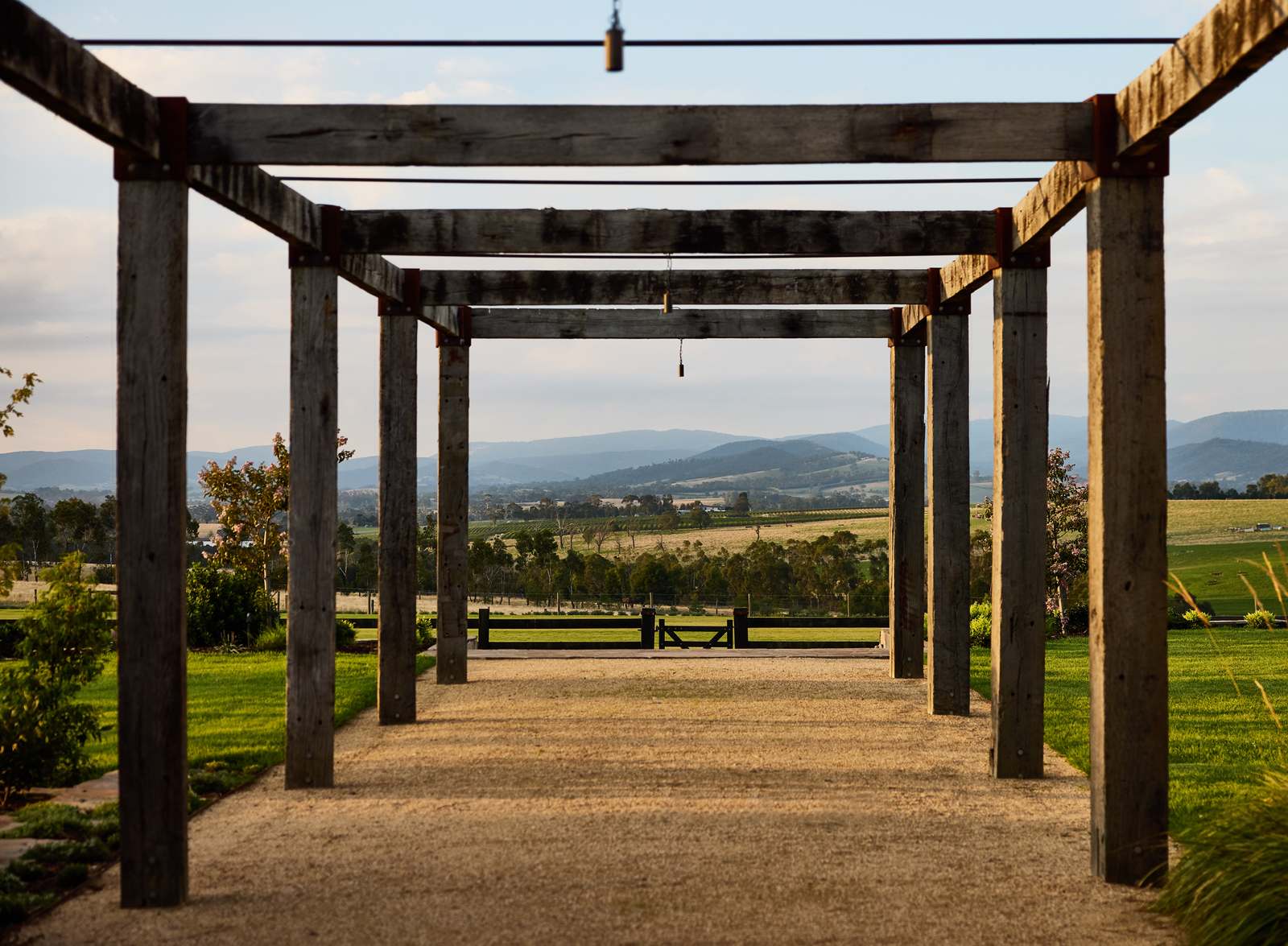 Recycled timber pergola framing a view across paddocks to the ranges beyond