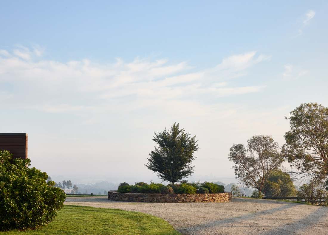 Gravel turning circle and dry stone planter in early morning mist, paddocks beyond
