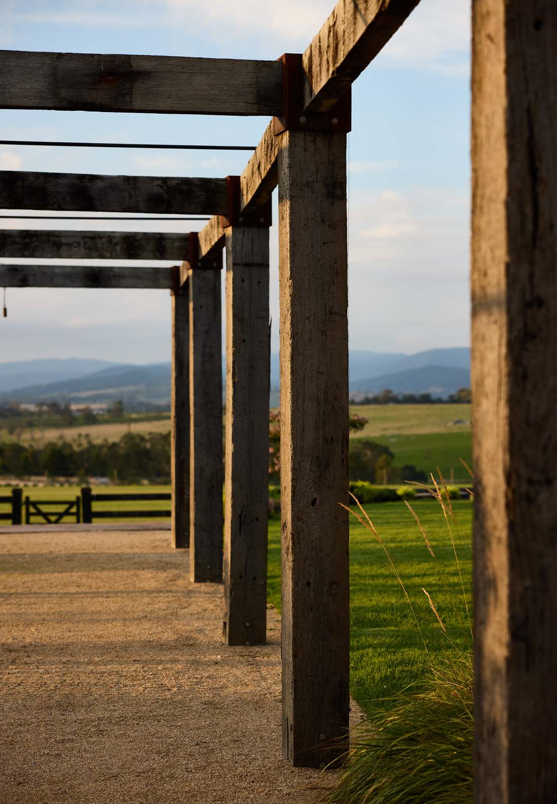 Recycled timber pergola posts in late sun, valley and ranges beyond
