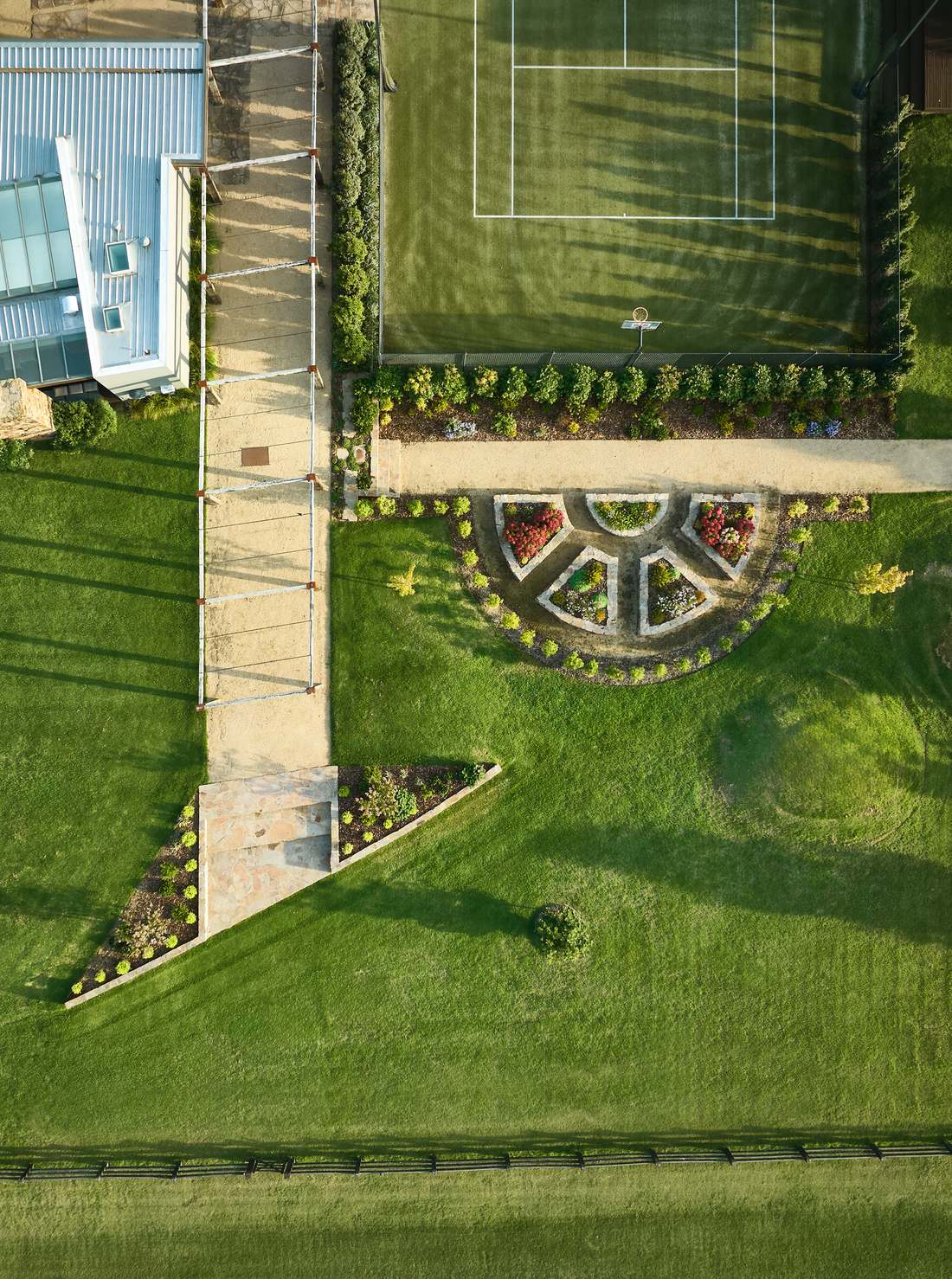 Overhead view of the pergola, the fan shaped stone beds and the corner of the tennis court