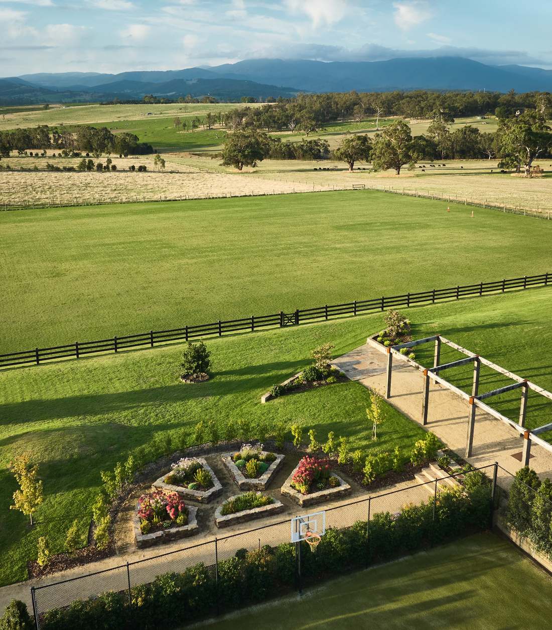 Aerial view over the arena and paddocks to the ranges, with the stone beds in the foreground