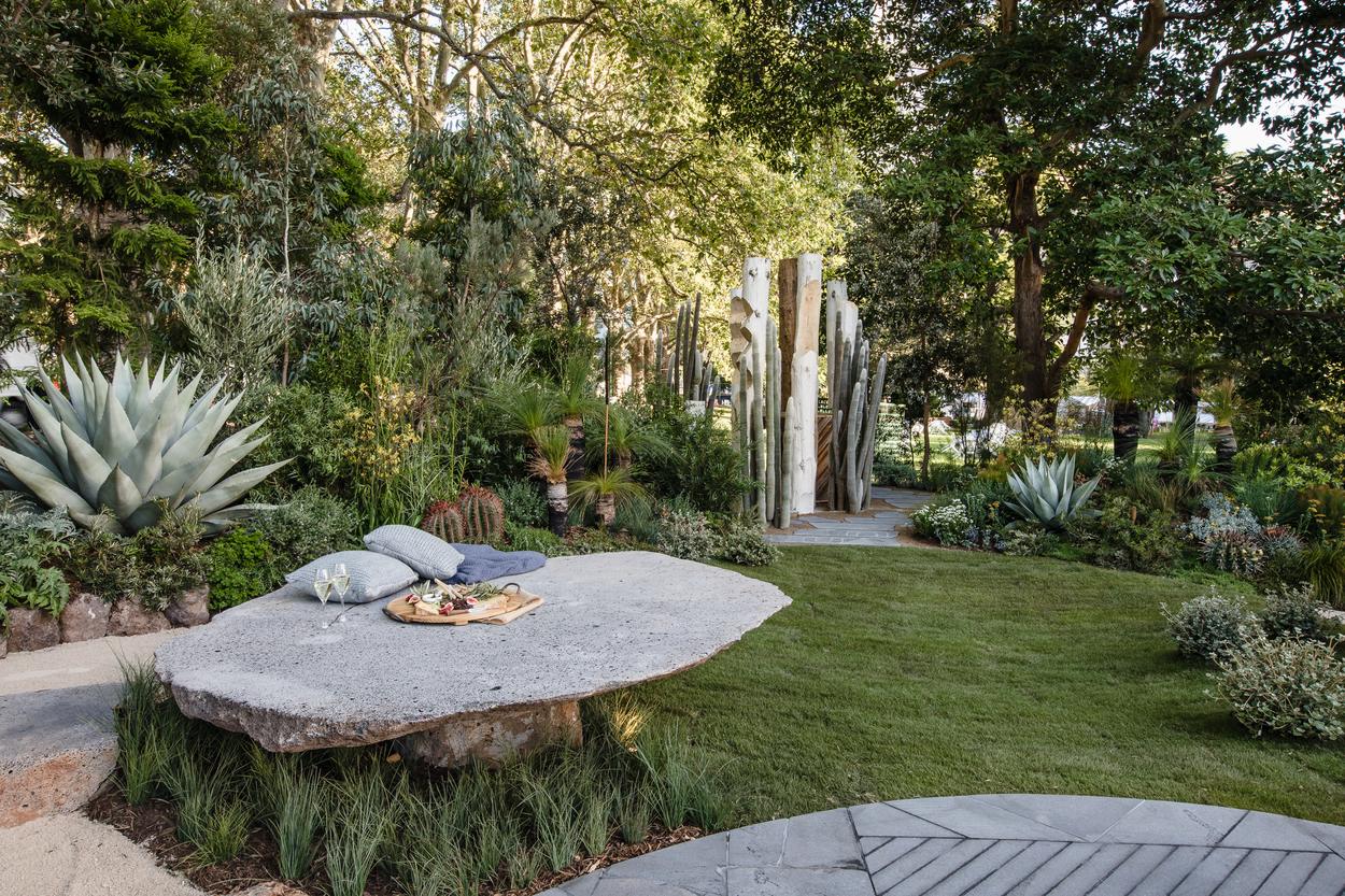 The stone table on the edge of the lawn, agave and grass trees behind