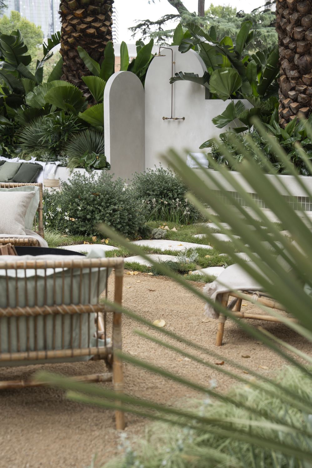 Looking across the cane loungers and gravel terrace toward the arched shower walls