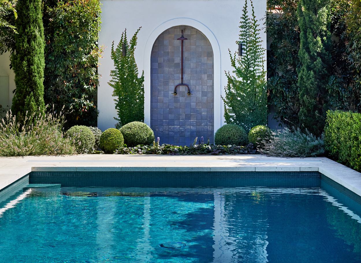 The pool looking across to the arched outdoor shower, pencil pines and lavender either side